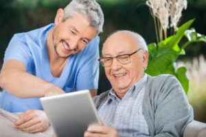 caregiver helping old man on tablet